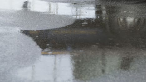 reflection of a passing truck in water on the tar road as rain drizzles at a steady pace, street in ireland