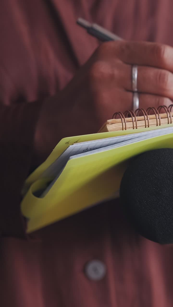 Close up hands woman journalist holding microphone and writing text in notepad