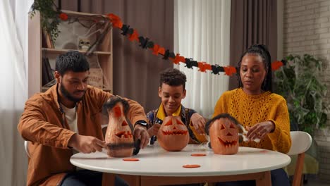 family carving halloween pumpkins together