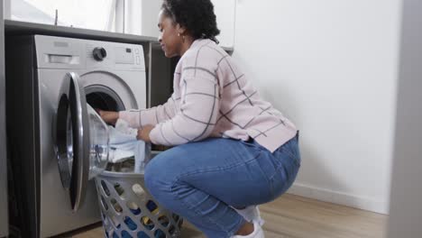 Afroamerikanische-Frau-Wäscht-Wäsche,-Nimmt-Saubere-Kleidung-Aus-Der-Waschmaschine,-Zeitlupe