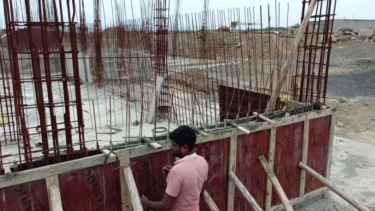 Panoramic video shot of vertical steel reinforcement bars (rebar) arranged in a grid pattern, indicating that concrete columns or walls are being constructed