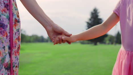 unknown woman holding girl hand outdoor. closeup mother and daughter hands.