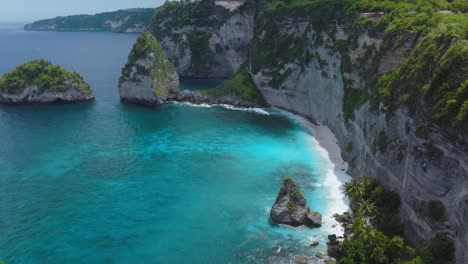 flying past jogglo viewpoint revealing turquoise water at diamond beach, nusa penida, aerial