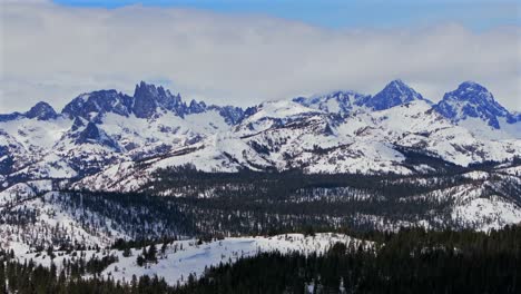 banner peak minaret summit pass mammoth mountains vista parallax winter aerial drone california group jagged towering snow covered peaks sunny storm inyo forest sierra nevada valley forward pan up
