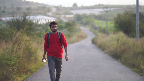 Young-man-drinking-water-from-bottle-during-walk-on-street-at-sunset