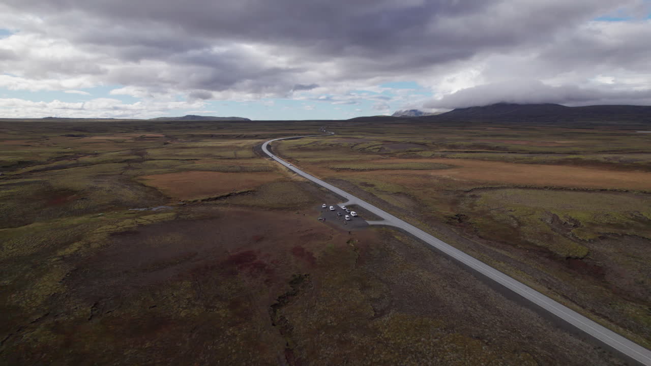 Vehicles parked on the side of a highway for scenic views of Iceland's volcanic landscape, aerial view