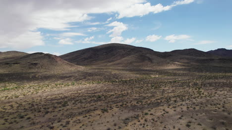 Aerial-ascending-footage-of-dry-landscape-with-hill-and-small-vegetation