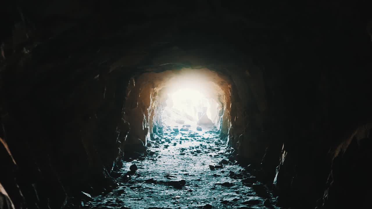 불분명한 사람들이 기다리고 있는 밝은 빛을 향해 앞으로 나아가는 동굴 같은 곳에서 촬영