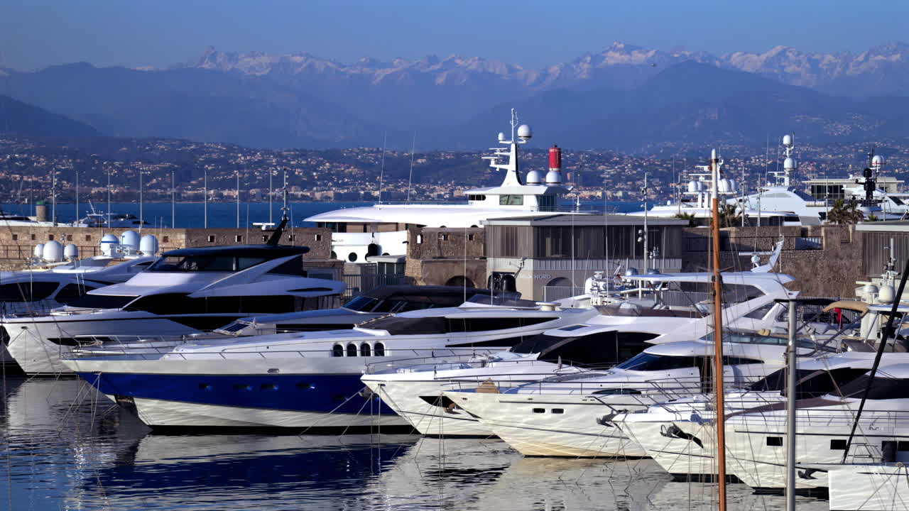 Cannes, France - March 3, 2025: Boats docked in the Cannes Marina with the mountains on the background