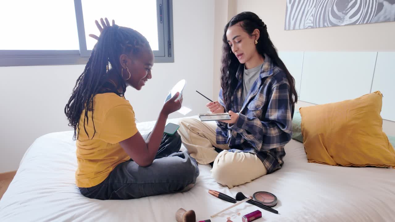 Two young women doing makeup in the bedroom