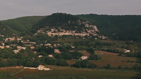 aerial approaching dolly establish of seguret in provence, france, featuring the village’s charming rooftops and scenic countryside views built up into forested hills