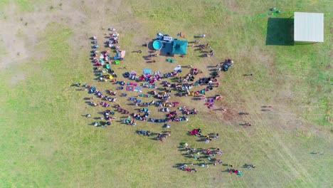 Descending-top-down-shot-of-crowd-with-people-getting-baptized-in-a-field