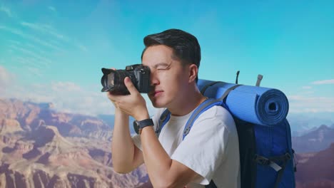 close up side view of asian male hiker with mountaineering backpack using a camera taking picture while traveling at the top of mountain
