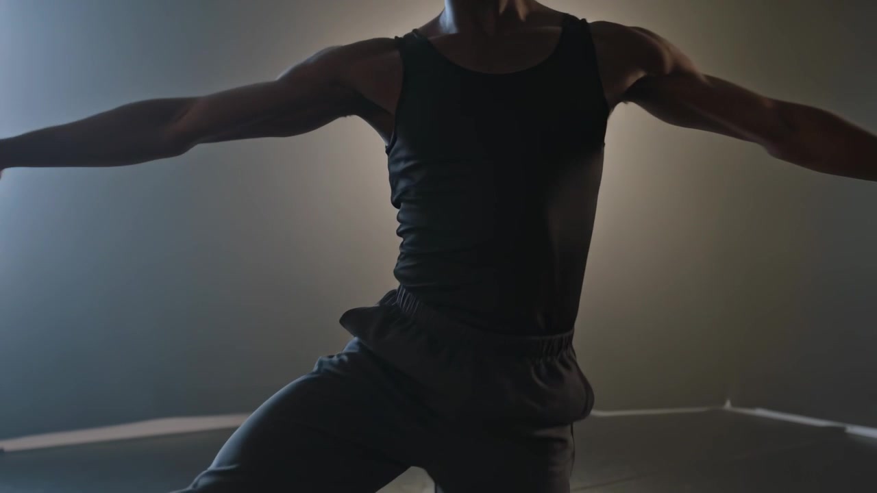 Swinging free leg forward, dancer wearing black tank pivoting in studio on marley floor, balancing