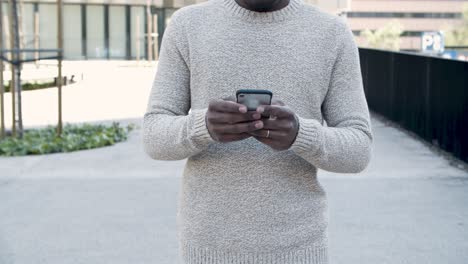 front view of man texting on smartphone during stroll