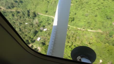 Aerial-coastline-view-from-the-window-of-a-small-light-aircraft,-fertile-tropical-farmland-vehicle-road-residential-property-Big-Island-Papua-New-Guinea