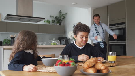 padre empresario en la cocina ayudando a los niños con el desayuno antes de ir a la escuela