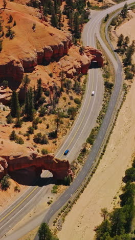 cars going under the rock arches on the highway in national park. sunny daytime footage over the arches canyons, utah, usa. vertical video