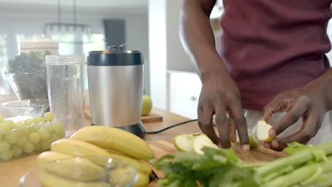 Midsection-of-african-american-man-preparing-healthy-smoothie-in-kitchen-at-home,-slow-motion