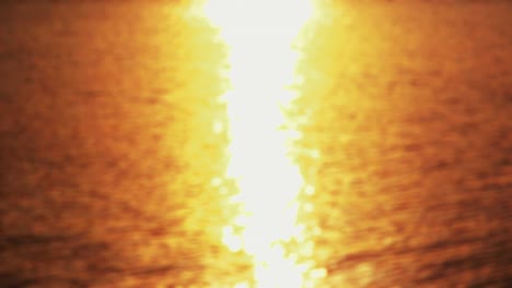 puesta de sol junto al mar - bucle sin costuras de una toma de 4k completamente desfocada de una superficie de agua ondulada con un hermoso bokeh de resplandores solares.
