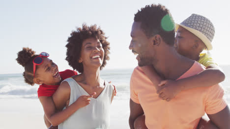 smiling african american family carrying and embracing on sunny beach
