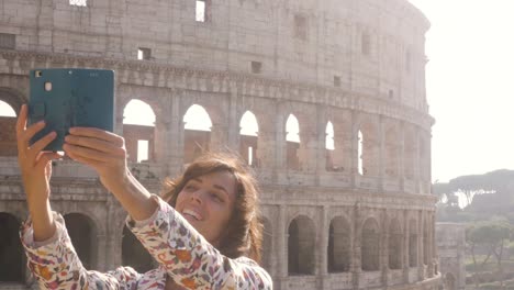 beautiful young woman in colorful fashion dress alone on hill with bike taking selfies with colosseum in rome with smartphone at sunset attractive elegant girl