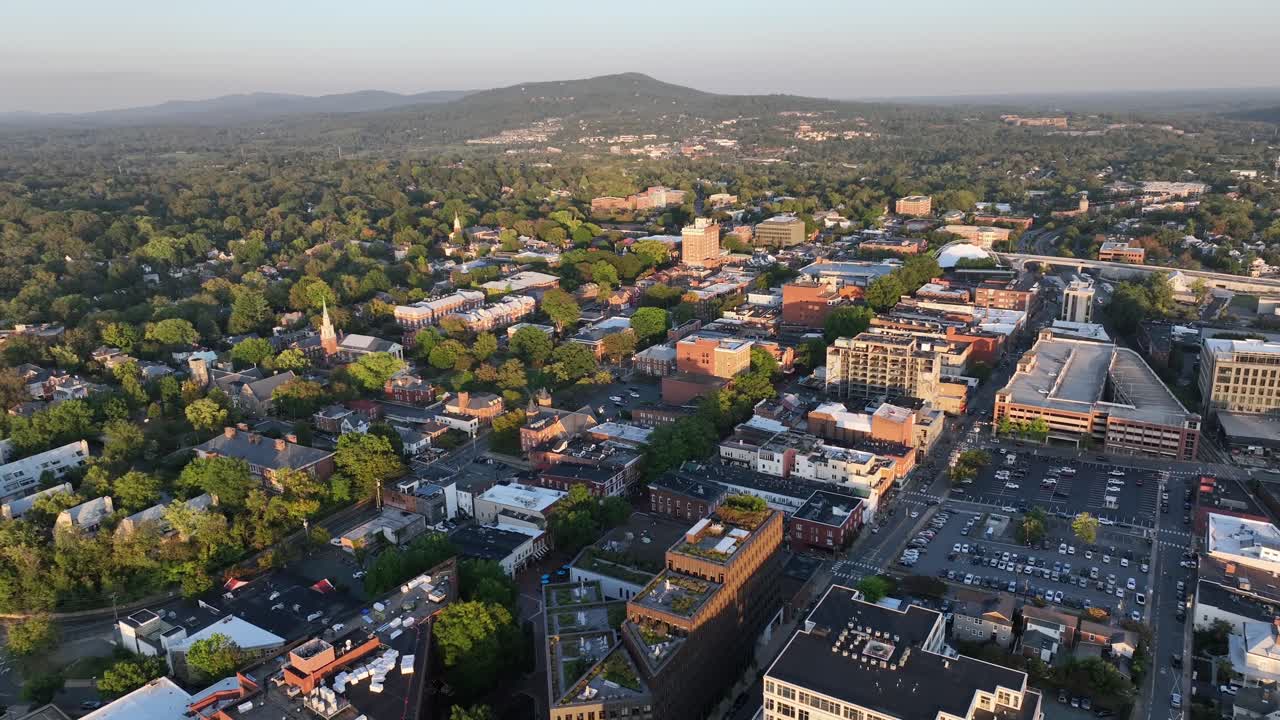 Aerial wide shot of american town with downtown and green trees at sunset. Autumn day with parking area. Wide shot.