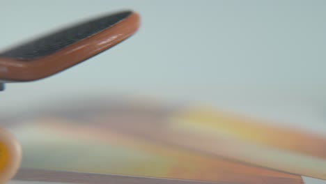 a hyper close-up macro detailed shot of a mini skateboard, tiny white wheels, riding fingerboard from right to left, finger slide, professional lighting, dreamy static cinematic 4k video