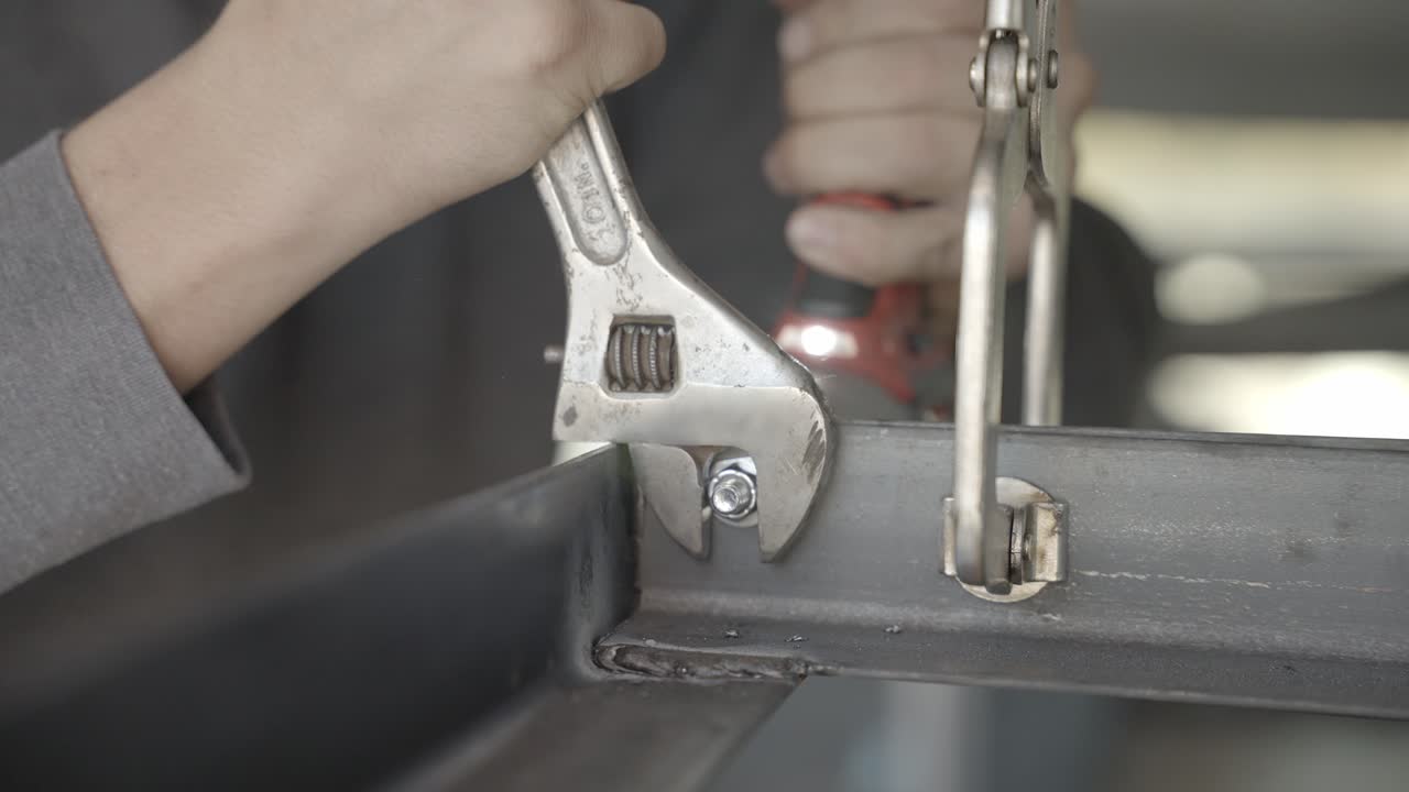 볼트가 금속 구조물에 뚫린 상태에서 육각 너트를 고정하는 조정 가능한 스패너