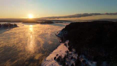 mist floating over water near bjorvika, oslo with golden hour sunset on horizon