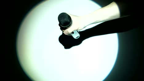 men's hand holding a microphone in the white light beam