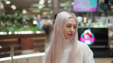 close up of stylish lady with pastel hair seated on bench by mosaic water fountain in modern mall, gazing thoughtfully at gentle fountain flow with soft bokeh lighting behind evoking serene mood