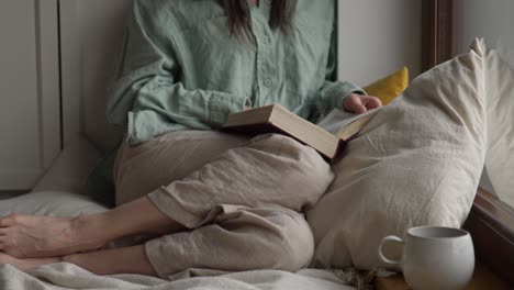 woman reading a book by the window