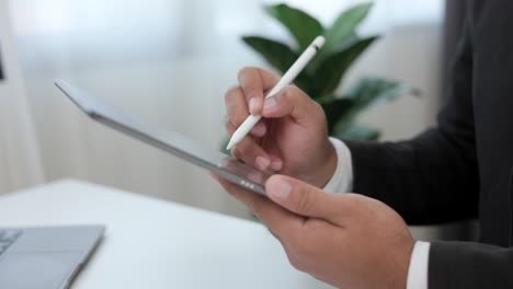 businessman using stylus pen signing contract on digital tablet at work in office indoors. close up hand write business agreement of contract. electronic signature on tablet computer.