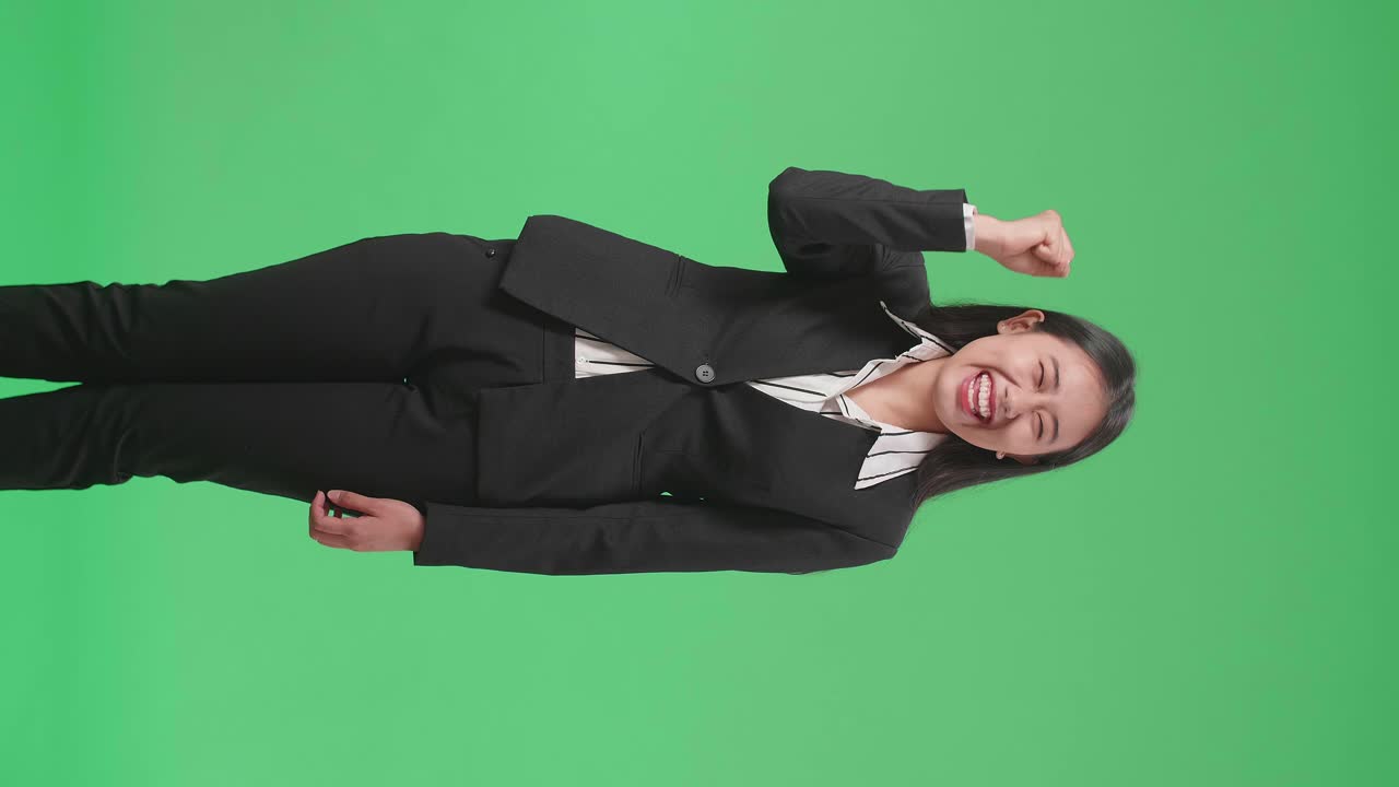 Happy Asian Business Woman Celebrating While Standing On Green Screen In The Studio