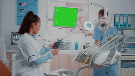 Stomatologist-watching-monitor-with-horizontal-green-screen