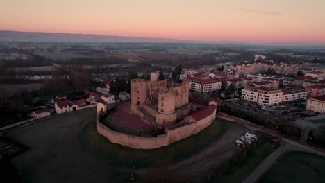 drone shot approaching montrond les bains castle during the sunrise with a beautiful golden hour, plaine du forez, loire departement, french countryside