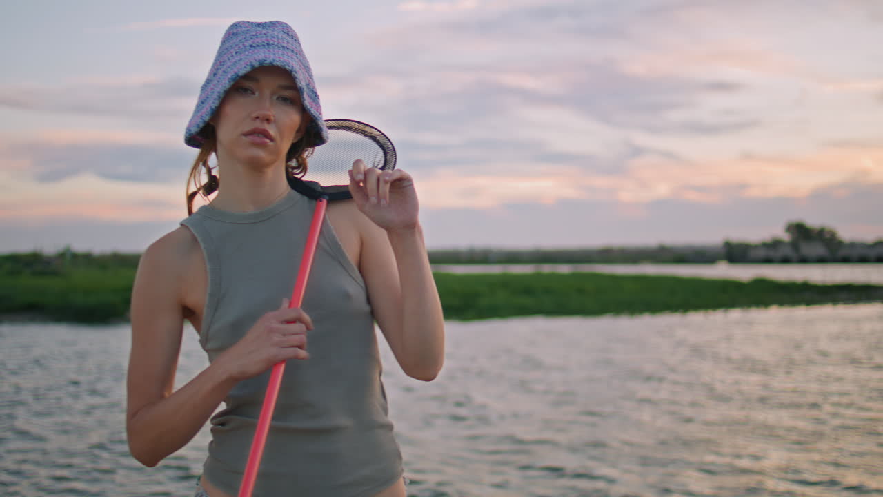 chica de la pesca pisando el agua en la noche de verano. relajada señora tranquila mantener la red de cuchara
