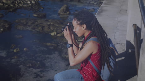 animación de puntos de luz sobre mujer biracial tomando fotos con cámara en el paseo marítimo