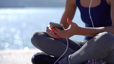 sporty young woman in earphones using mobile phone outdoor