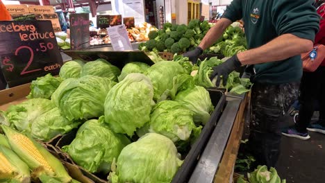 man arranging vegetables at market stall