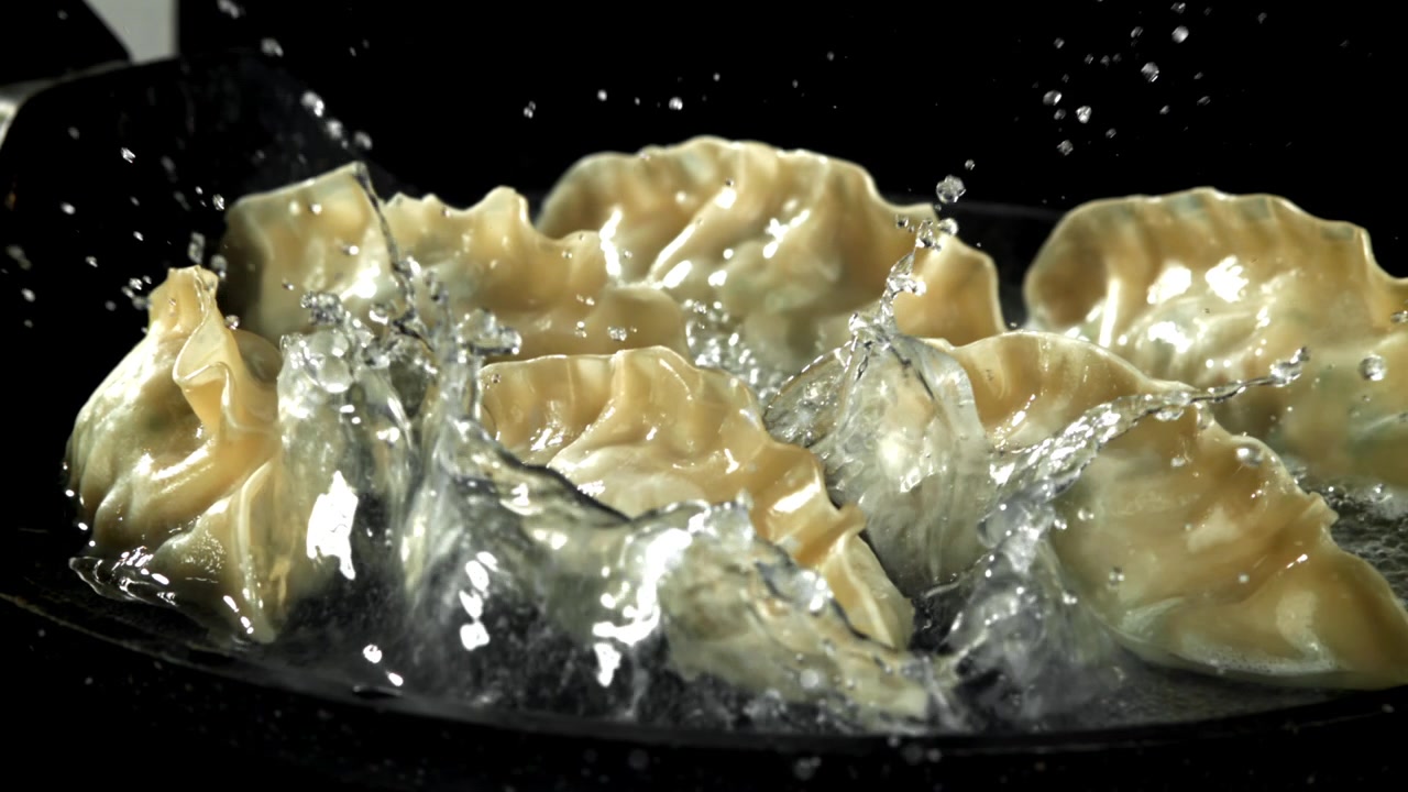 Slow Motion of Dumplings Frying in a Hot Pan with Splashing Water