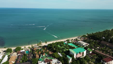 Aerial-pan-right-over-Maret,-boats-sailing-on-coast,-Koh-Samui,-Thailand