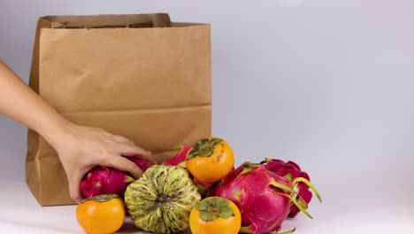 colocando frutas a mano en una bolsa de papel