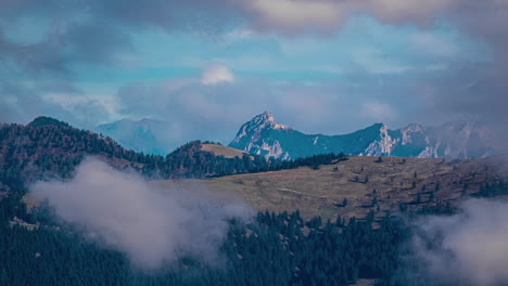 Clouds-rise-and-blow-in-the-wind-above-coniferous-forest-with-rugged-ridgeline-mountains-behind