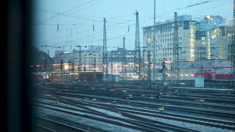 view from a train overlooking busy railway tracks and urban buildings at dusk