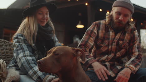 cute pit bull dog sitting with owners by bonfire