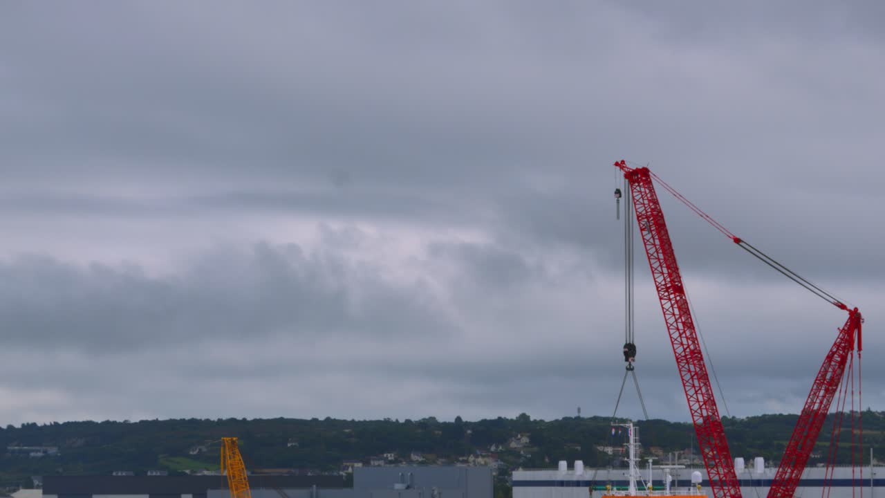 grúa en el puerto de cherbourg en un día nublado preparándose para cargar buques de carga y transporta bienes en todo el mundo 4k