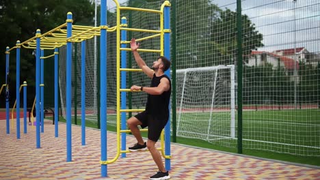 hombre entrenando los músculos del núcleo con elevación de piernas en un estante de escalera vertical en un centro de gimnasio al aire libre