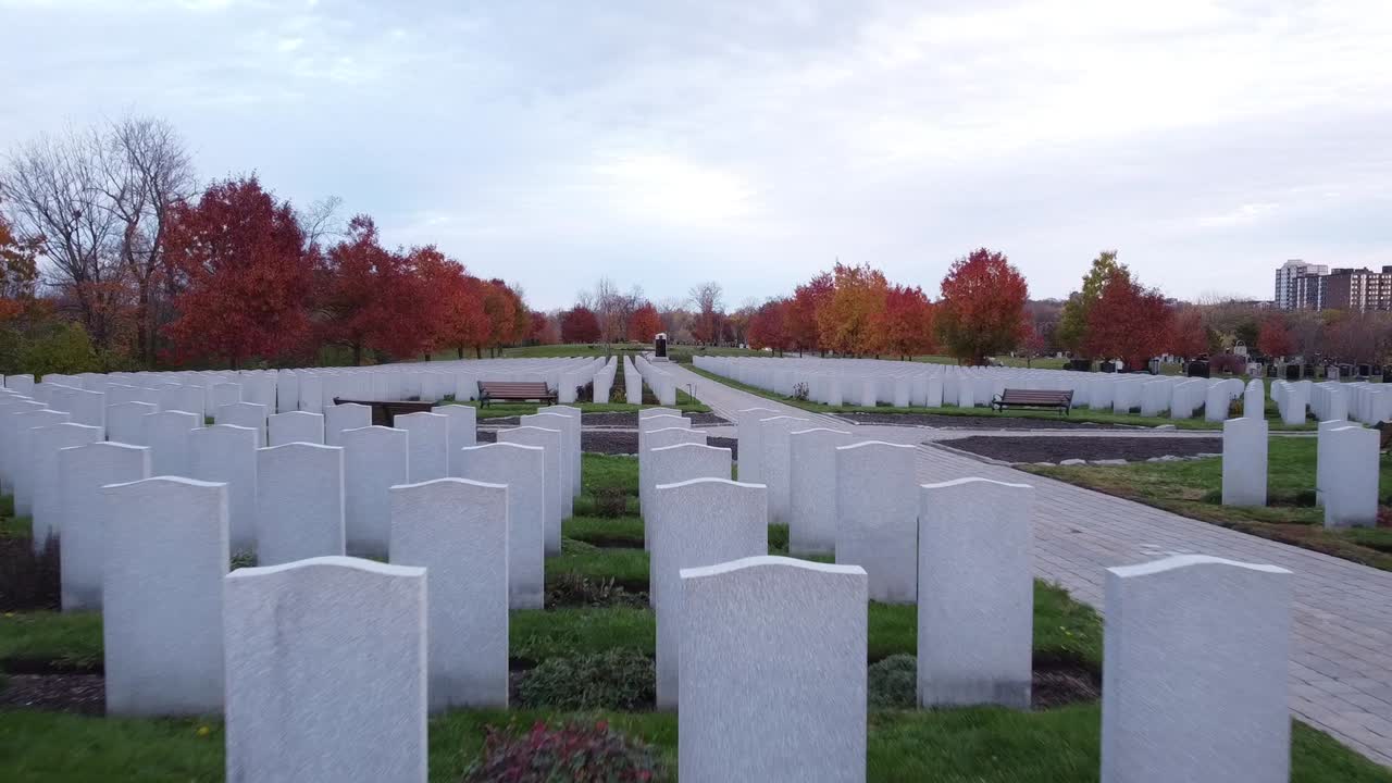 Un drone vola sopra file di lapidi in un cimitero durante l'autunno.